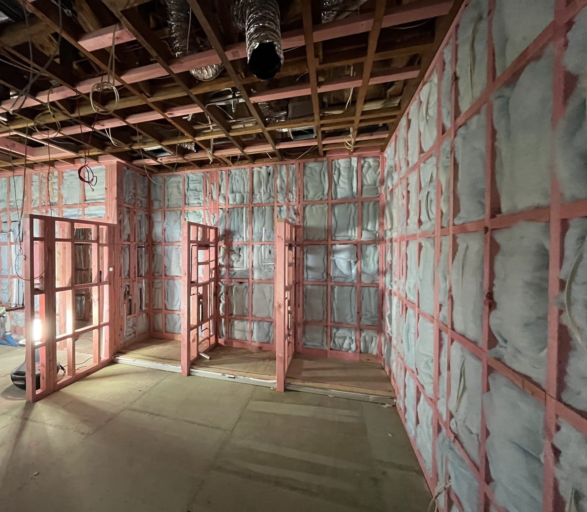 Interior under construction, with timber framing, wall insulation and ceiling services roughed in